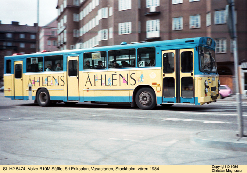 sl6474_19840000.jpg - Om det var samma dag som jag tog den första bilden som jag sedan tog denna, vet jag inte men jag har tydligen placerat mig vid S:t Eriksplan och tagit en bild av denna H2, Volvo B10M med Säffle-kaross, i full fart. Det här var min absoluta favorit bland busstyper vid den här tiden. Just det här exemplaret var reklammålat men typen fanns i många exemplar i den vanliga oxblodsröda färgen också.